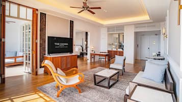 A spacious living area with a television, wooden furniture, and a ceiling fan.
