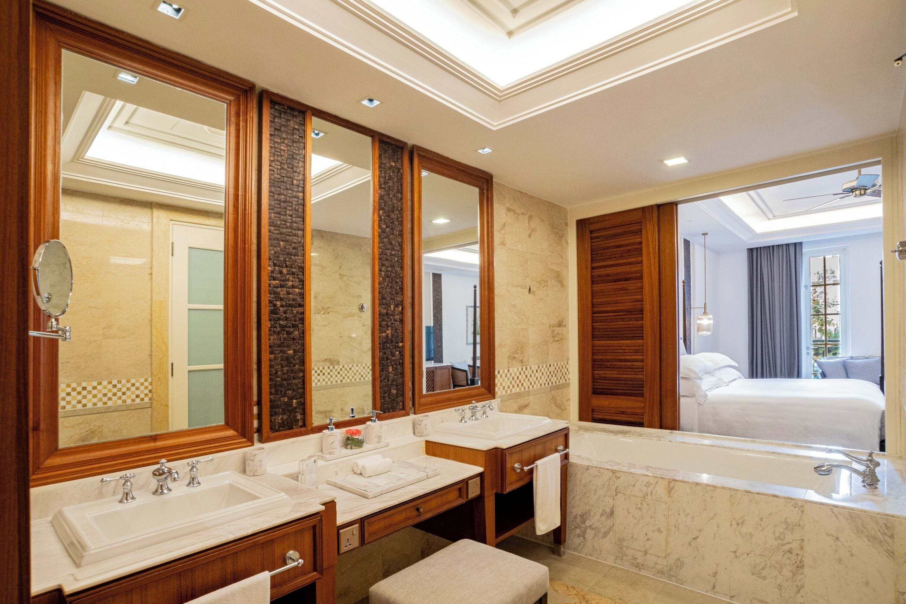 A modern bathroom with two sinks, a large mirror, and a bathtub.