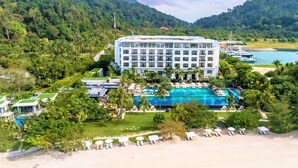 A hotel with a large pool, beachside lounge chairs, and a view of the sea and mountains. - The Danna Langkawi - A Member of Small Luxury Hotels of the World  (Langkawi)
