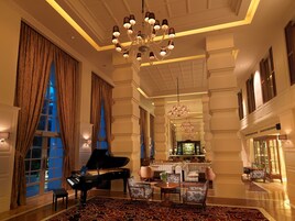 Un vestíbulo imponente con un piano de cola, elegantes candelabros y una zona de bar.