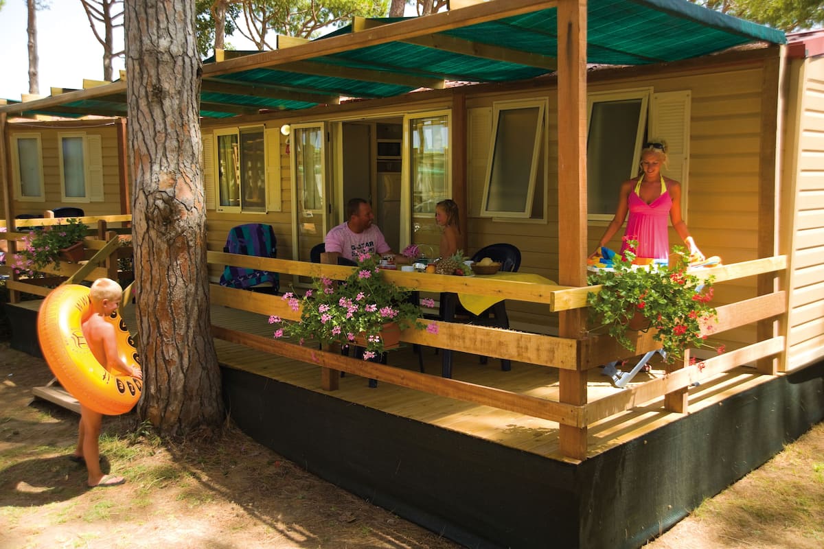 A wooden cabin with a deck, outdoor seating, and potted plants.