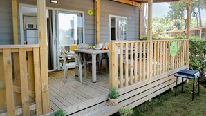 A wooden deck with a table and chairs, a grill, and a small garden area.