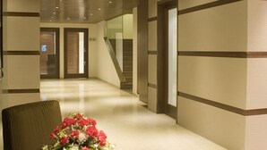 A hotel lobby with a glass table, chairs, a staircase, and a fire alarm on the ceiling. - Shervani Hotel Nehru Place (New Delhi)