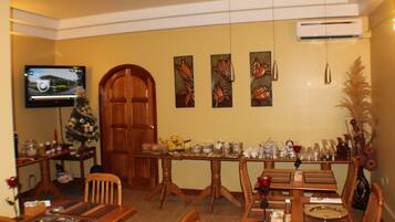 Un'area pranzo con un tavolo di legno apparecchiato per sei persone, un albero di Natale e una televisione appesa al muro.