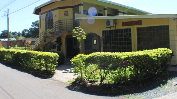 A two-story building with a yellow facade, a staircase leading to the upper floor, and a sign that reads "ATVIVE ABODE".