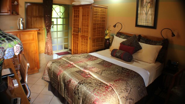 A bedroom with a bed, a wardrobe, a desk, and a chair. - Native Abode (Crown Point)