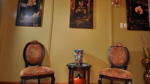 A hallway with two upholstered chairs, a small table with a pumpkin, and a chandelier. - Native Abode (Crown Point)