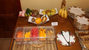 A table with various fruits and a fruit container.