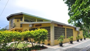A yellow building with a green roof, multiple windows, and a staircase leading to an upper level. - Native Abode (Crown Point)