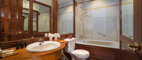 Un baño con tocador de madera, un espejo grande, un lavabo, un inodoro y una bañera.
