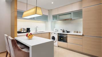 Una cocina moderna con una isla central, electrodomésticos integrados y una lámpara colgante.