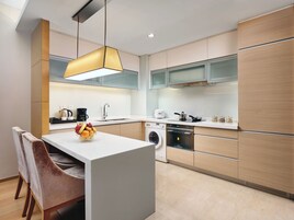 Una cocina moderna con una isla central, electrodomésticos integrados y una lámpara colgante.