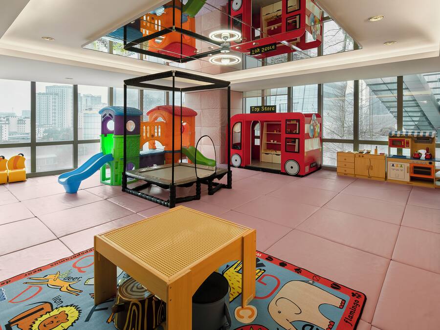 Un área de juegos interior amplia con un trampolín, estructuras de juego y una tienda de juguetes.