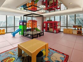 Un grand espace de jeux intérieur comprenant un trampoline, des structures de jeu et un magasin de jouets.