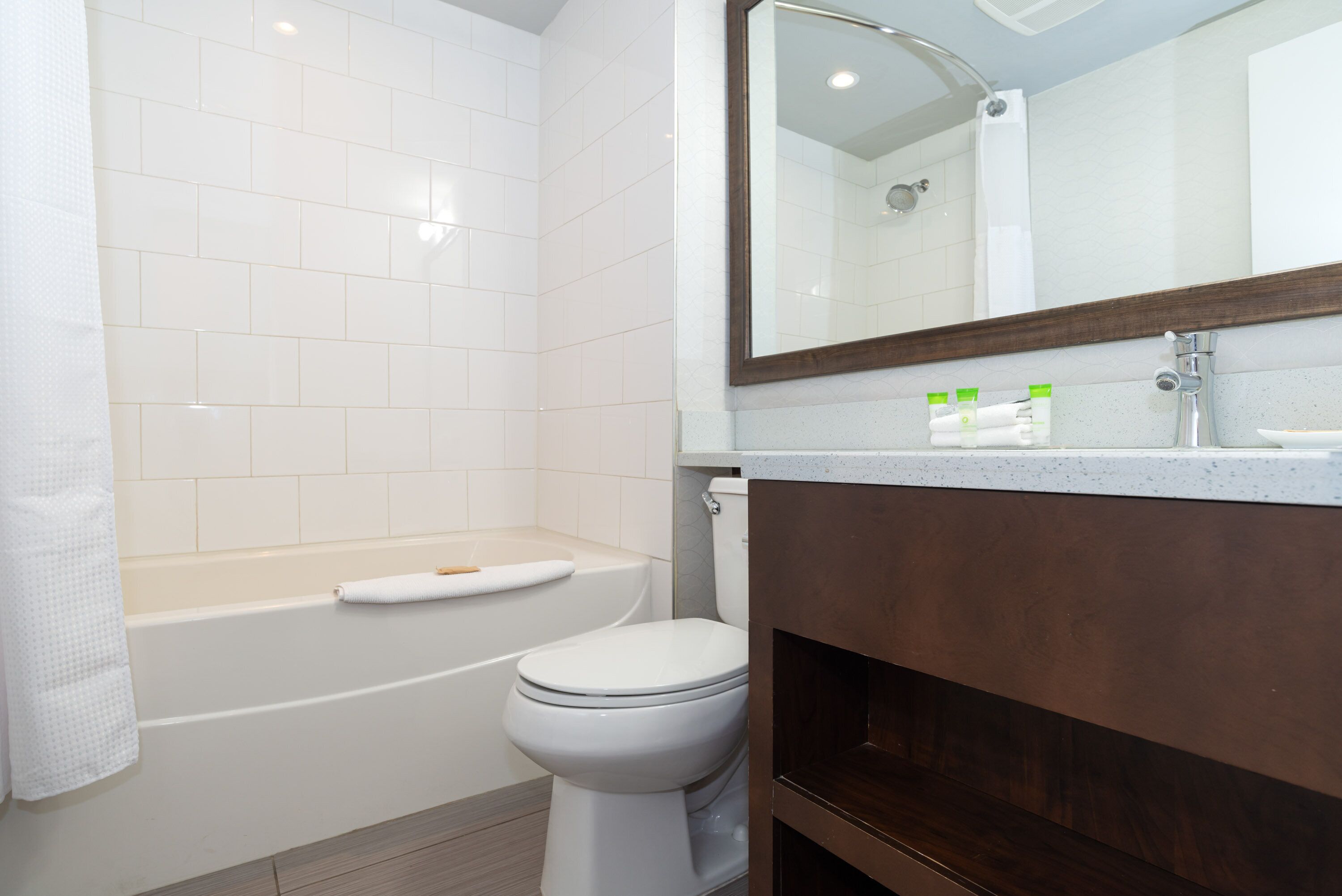 Un baño con inodoro blanco, bañera y tocador con espejo.