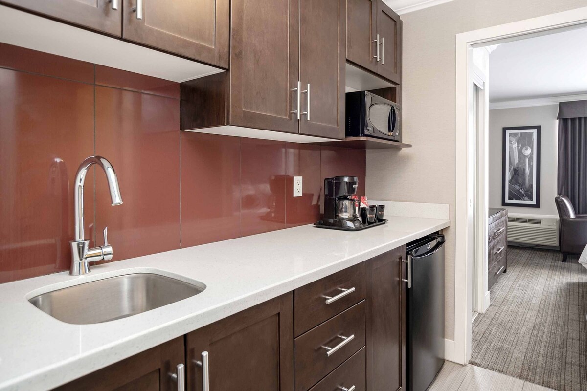 Una cocina moderna con un lavamanos de acero inoxidable, armarios de madera y un microondas.