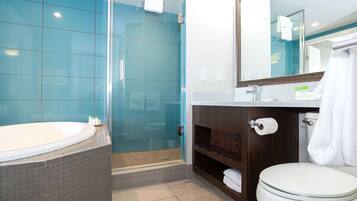 Une salle de bain moderne dotée d’une douche à parois de verre, d’une baignoire sur pieds et de toilettes avec un miroir au-dessus.