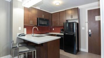 A modern kitchen with wooden cabinets, a black refrigerator, a microwave, and a sink.