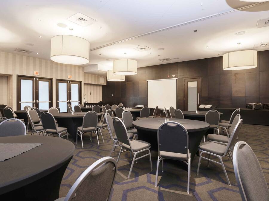 A conference room with multiple tables and chairs, a whiteboard, and a clock on the wall.