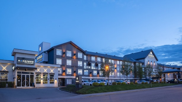 A hotel with a modern design, featuring a large parking area and multiple entry points.
