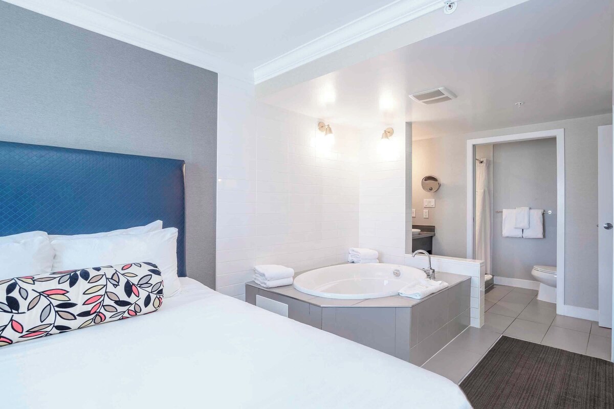 Een moderne hotelkamer met een groot bed, een badkuip, een wastafel en een badkamer.