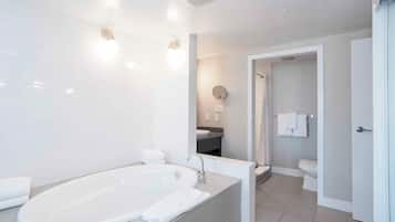 A modern bathroom with a large bathtub, a sink, and a toilet.