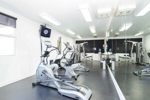 Un gimnasio con bicicletas estáticas, elípticas y máquinas de pesas.