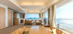 A modern hotel room with a dining area, a sofa set, a TV, and a view of the sea. - Diamond Setouchi Marine Hotel (Tamano)