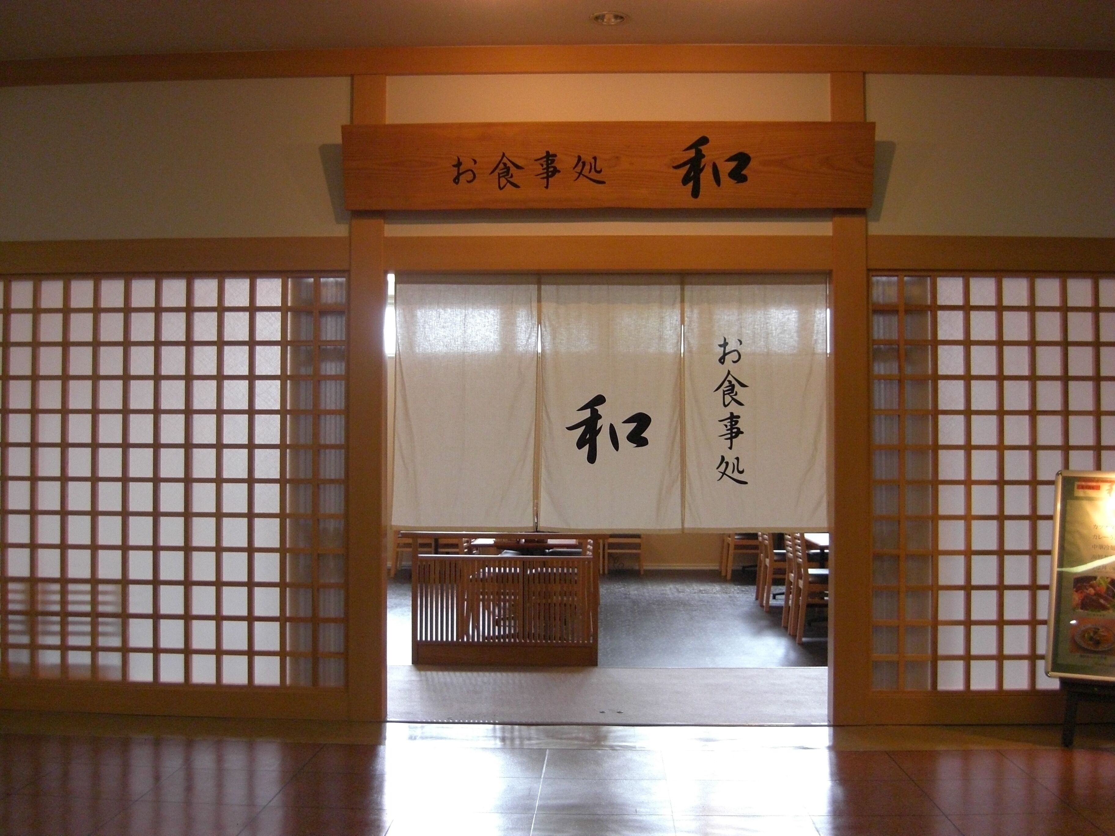 Een traditionele Japanse kamer met tatami vloeren, schuifdeuren en een houten bord met Japanse tekens.