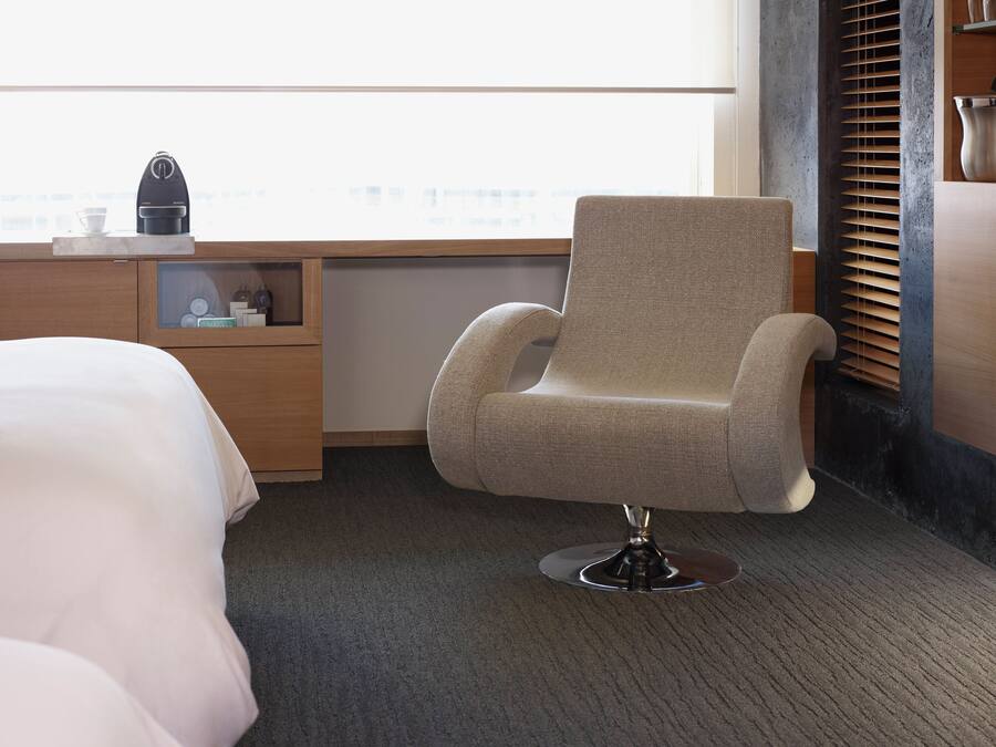 Una habitación de hotel moderna con una cama individual, un escritorio con cafetera y una ventana con persianas.