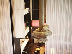 A modern interior with a unique hanging light fixture, a visible bar area, and a seating arrangement. - Le Germain Hotel Maple Leaf Square (Toronto)