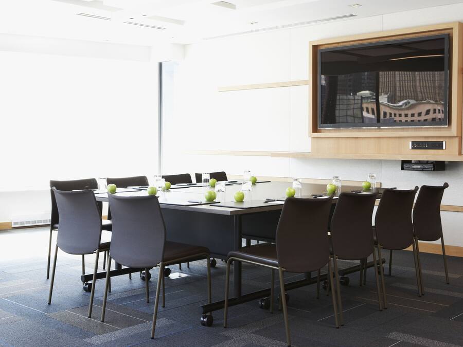 A conference room with a large table, chairs, and a mounted television.