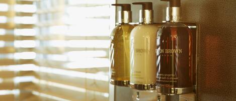 A wall-mounted dispenser with three bottles of BROWDON BROWN London bath and shower products.