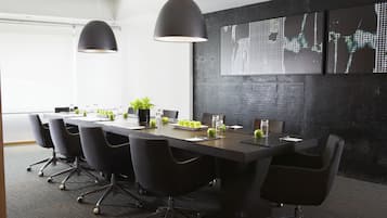 A conference room with a long table, black chairs, and two pendant lights.