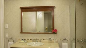 A bathroom with a double sink vanity, a mirror, a glass shower enclosure, and a bathtub.