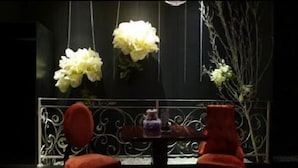 A dining area with a table and two red chairs, a black backdrop, and white flowers. - Nanjing Vogue Boutique Motel (Nanjing)