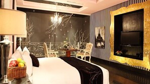 A modern hotel room with a large bed, a flat-screen TV, a chandelier, and a dining area with chairs and a table. - Nanjing Vogue Boutique Motel (Nanjing)