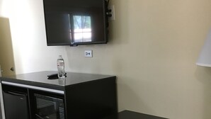 Una kitchenette compacta con un microondas, un refrigerador pequeño y una botella de agua en la encimera.