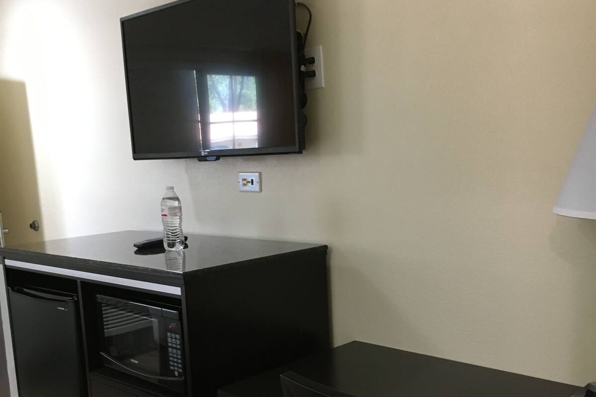 A compact kitchenette with a microwave, a small refrigerator, and a water bottle on the counter.
