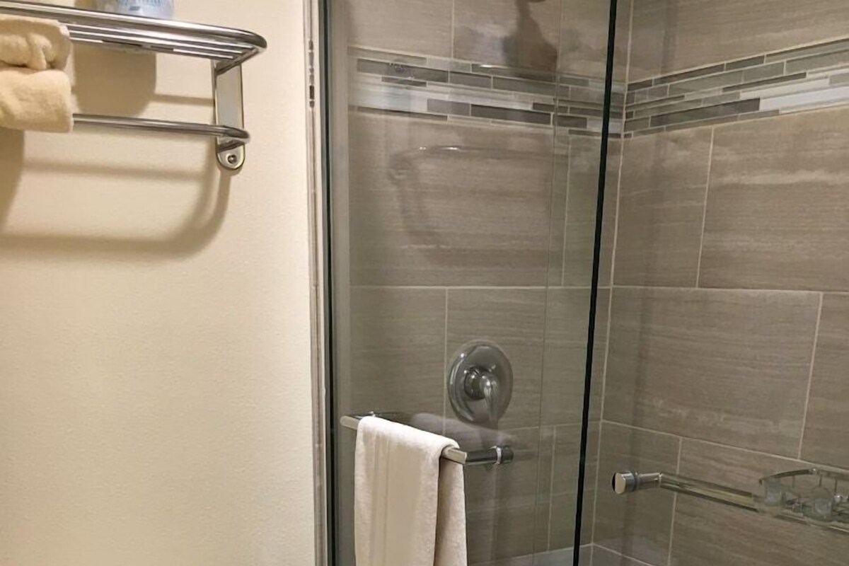 Un baño con inodoro, cabina de ducha con mampara de vidrio y un perchero para toallas.