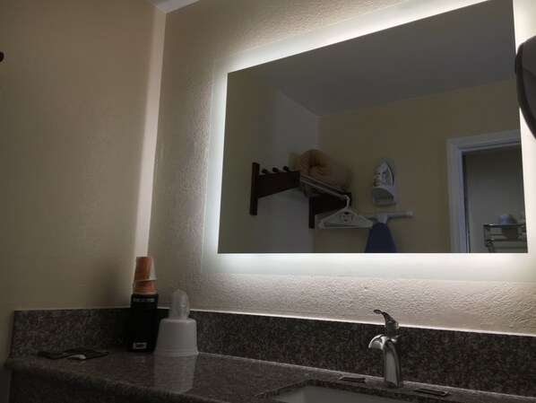 Une salle de bain avec un comptoir en granit, un lavabo, un miroir et un porte-serviettes.