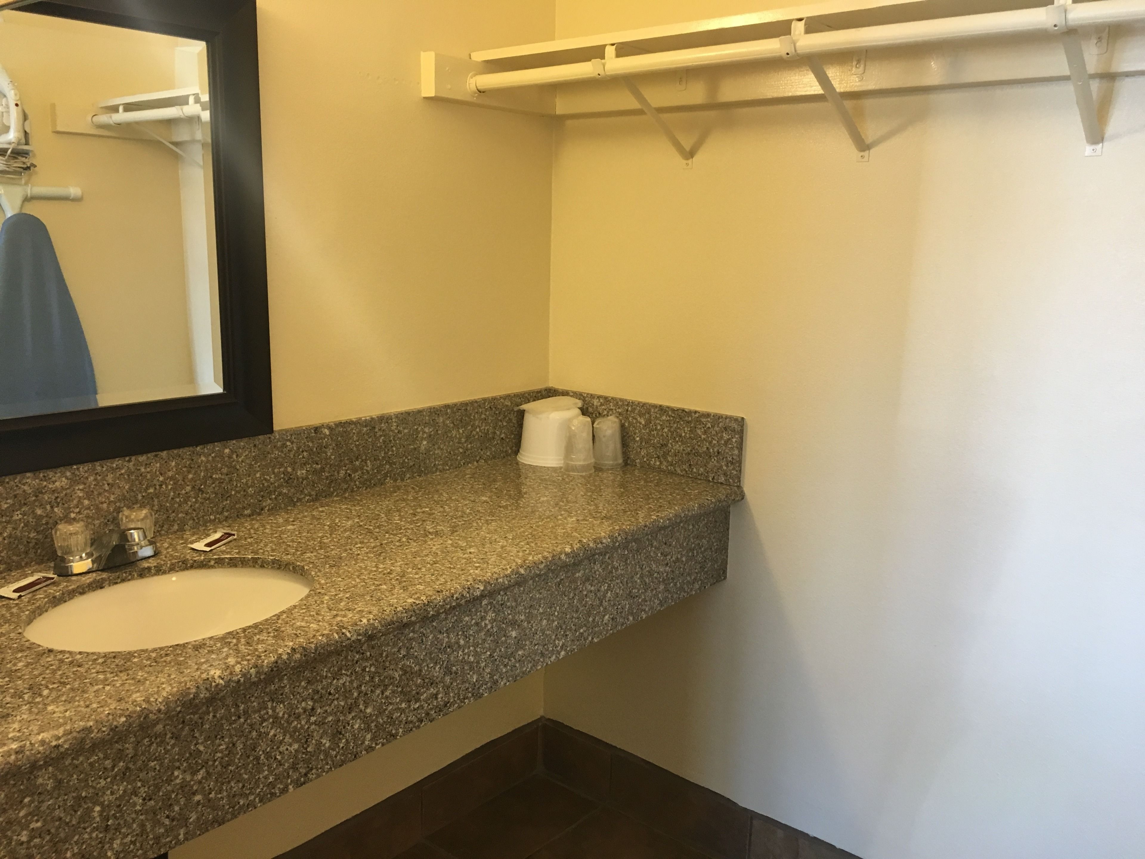 A bathroom with a granite countertop, a sink, a mirror, and a towel rack.