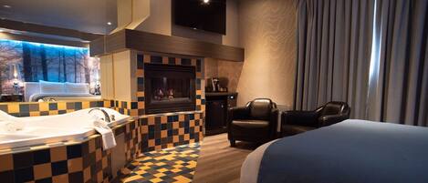 Una habitación de hotel con piso a cuadros, una cama grande, una chimenea, un televisor y vistas a árboles por la ventana.