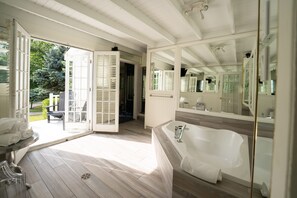 Une salle de bain spacieuse avec une grande baignoire, une douche à l’italienne et un grand miroir.