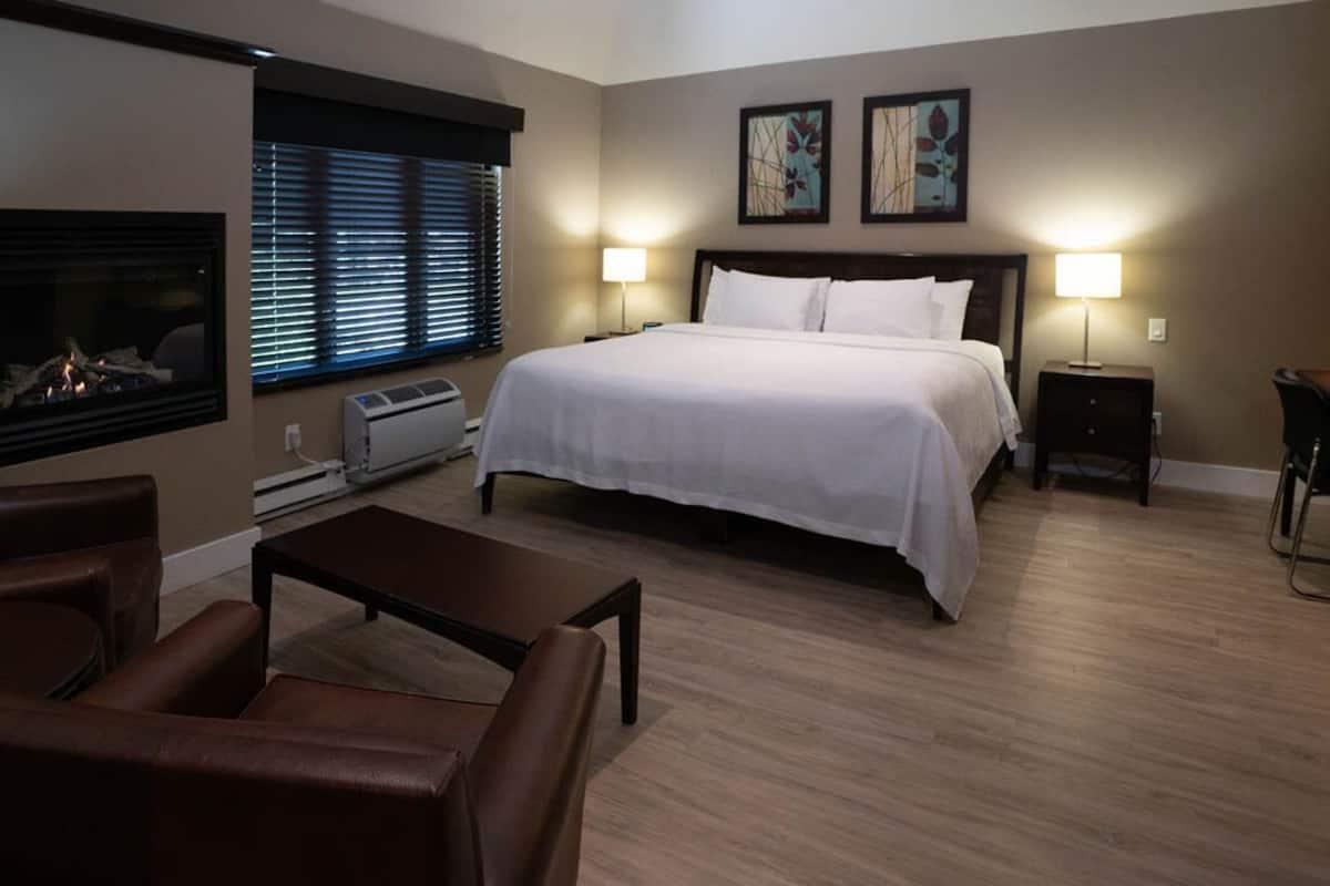 Una habitación de hotel con cama, chimenea, escritorio y una silla.