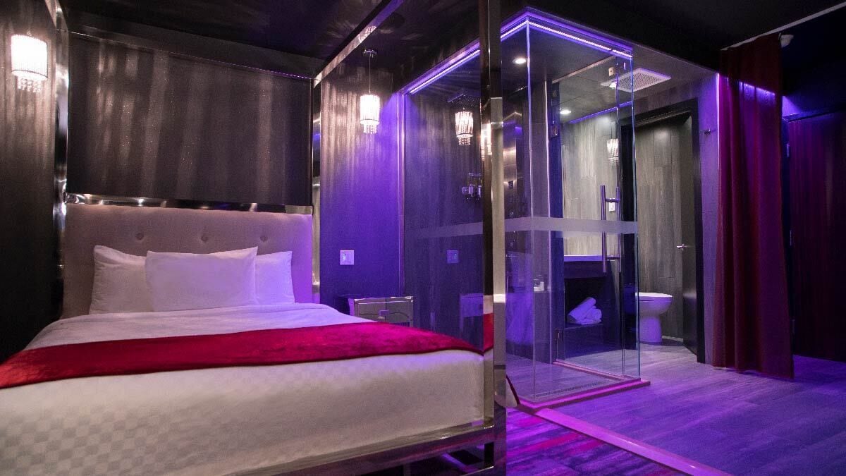 A modern bedroom with a large bed, a glass-enclosed shower, and a visible bathroom.