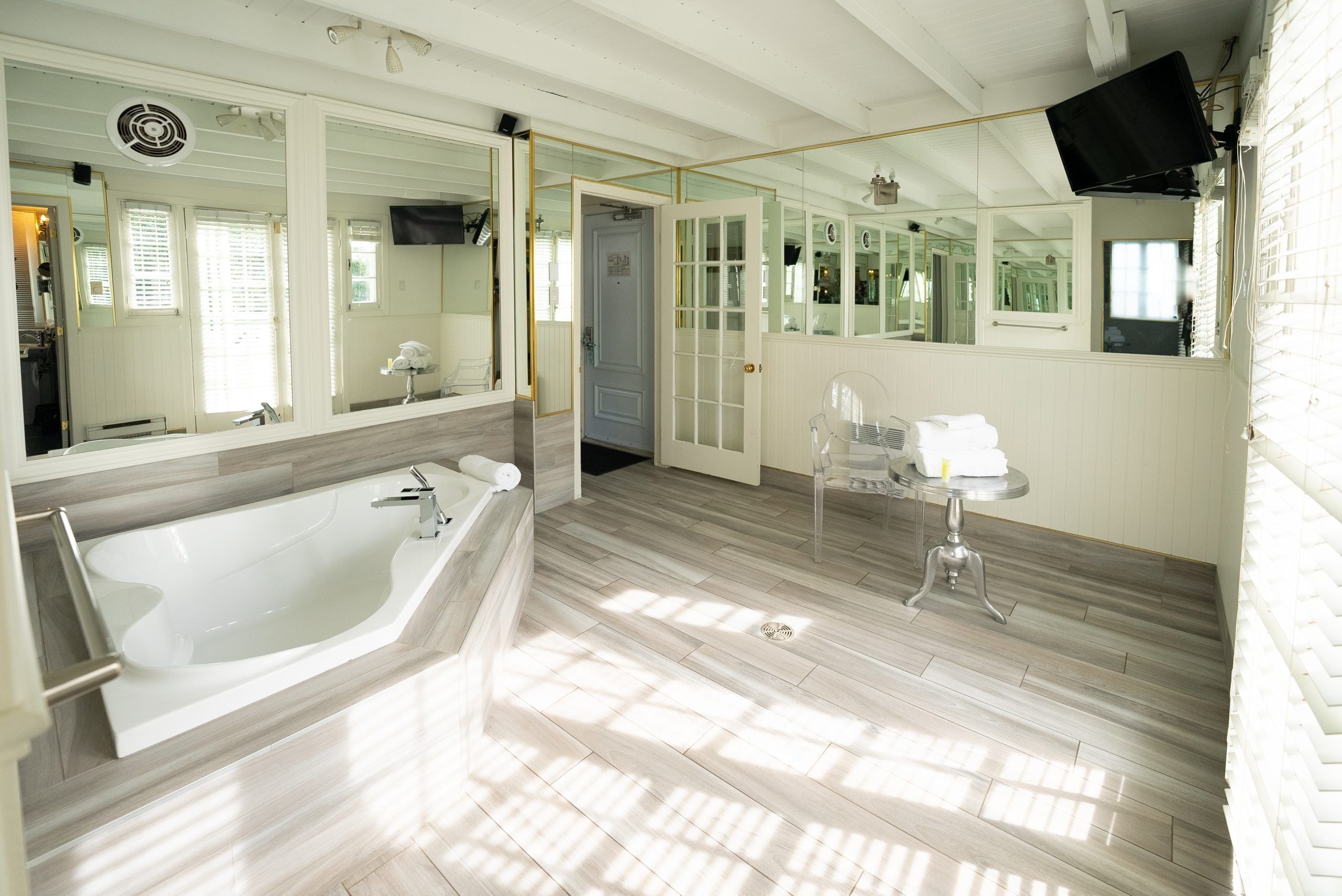 A spacious bathroom with a large bathtub, a sink, and a mirror.