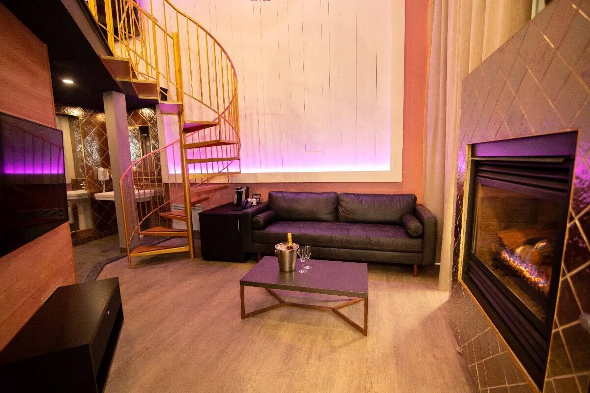 Una sala de estar moderna con una escalera espiral, una chimenea y un sofá.