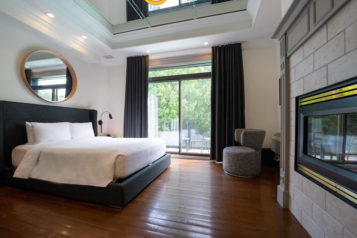 Una habitación de hotel moderna con una cama grande, un espejo redondo, una zona de estar y un televisor en la pared.