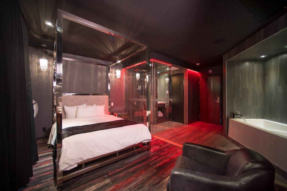 Una habitación de hotel moderna con una cama grande, baño independiente y zona de estar.